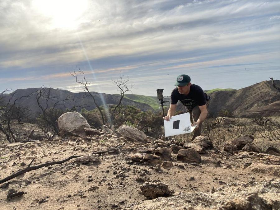 The artist setting up a special camera in a dry and burnt landscape.